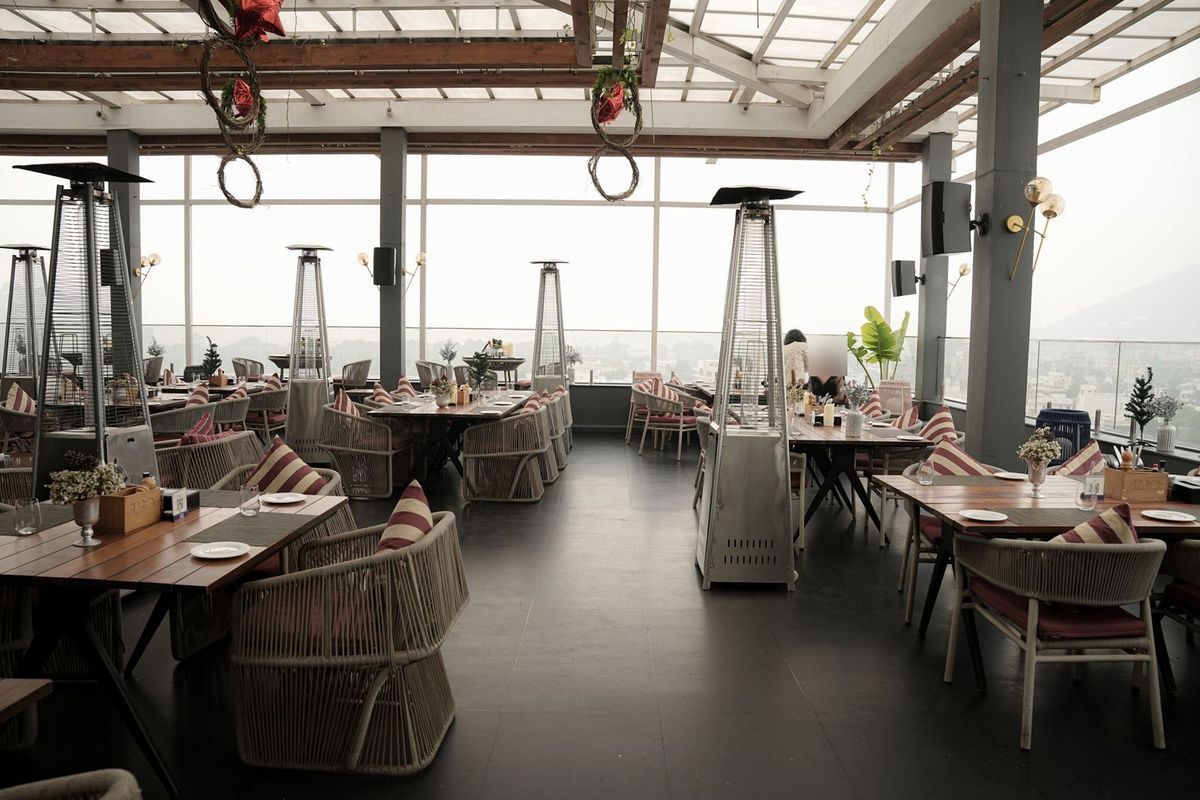 Terraza acristalada en una azotea con setas de calor de gas piramidales junto a las mesas