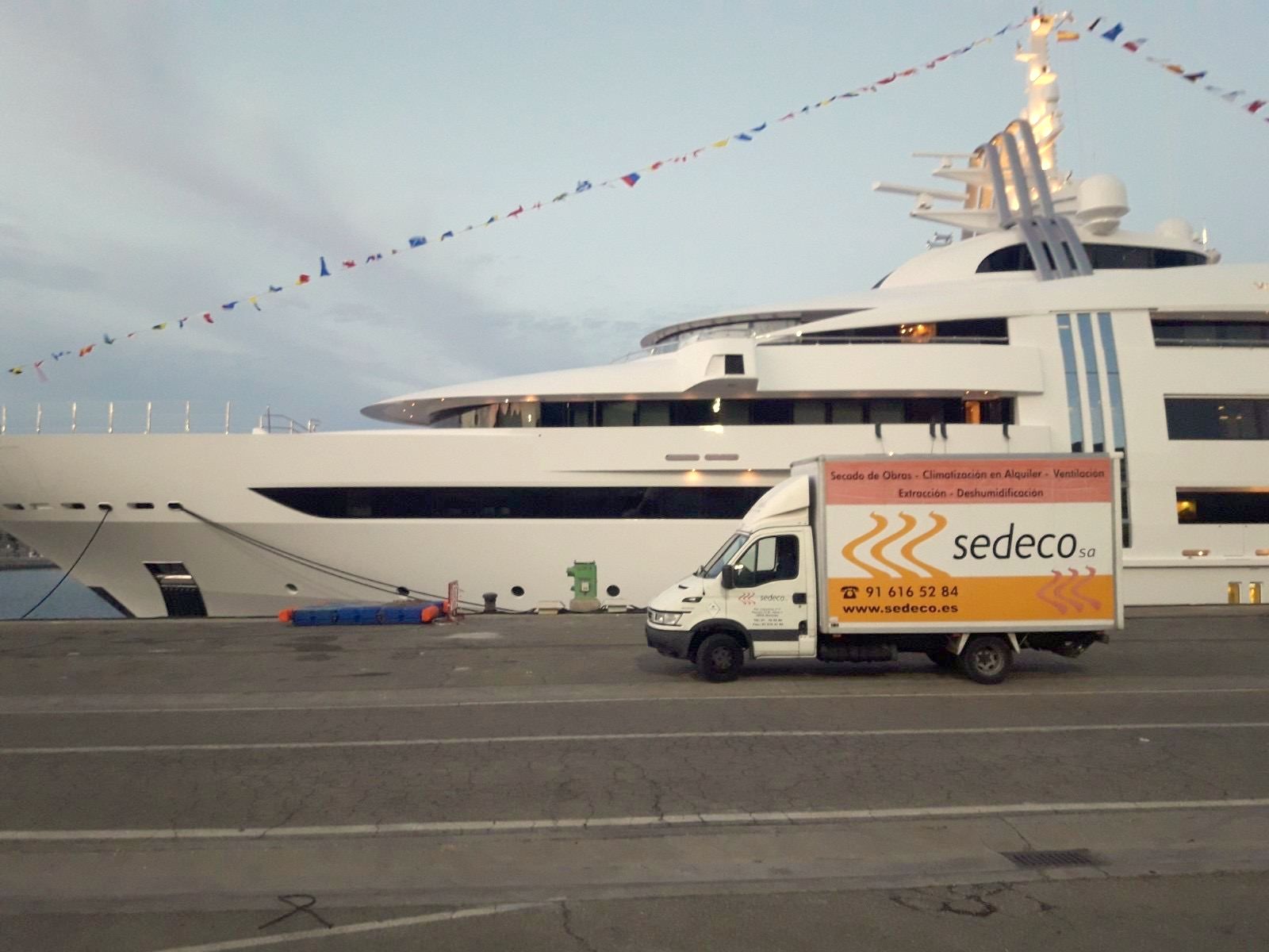 Furgoneta rotulada de SEDECO en un puerto, junto a un yate, durante un evento